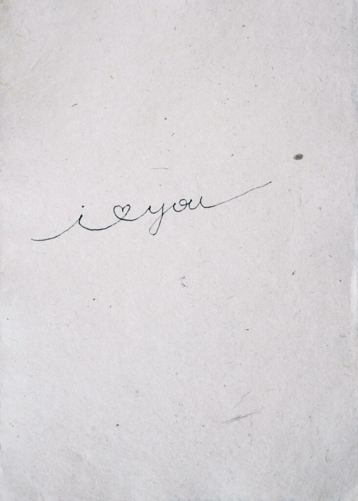 Close-up of a cursive 'I love you' handwritten on paper, conveying simplicity and affection.